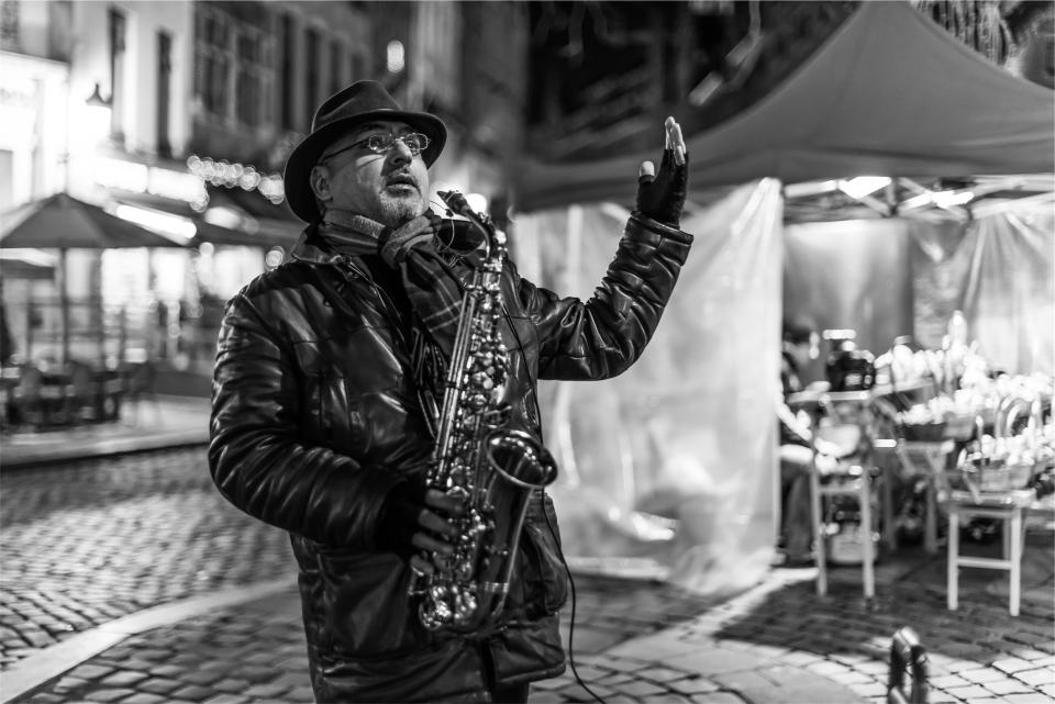 musician, street performer, saxophone, music, musical instrument, cobblestone, man, guy, hat, fedora, gloves, leather jacket, black and white, streets