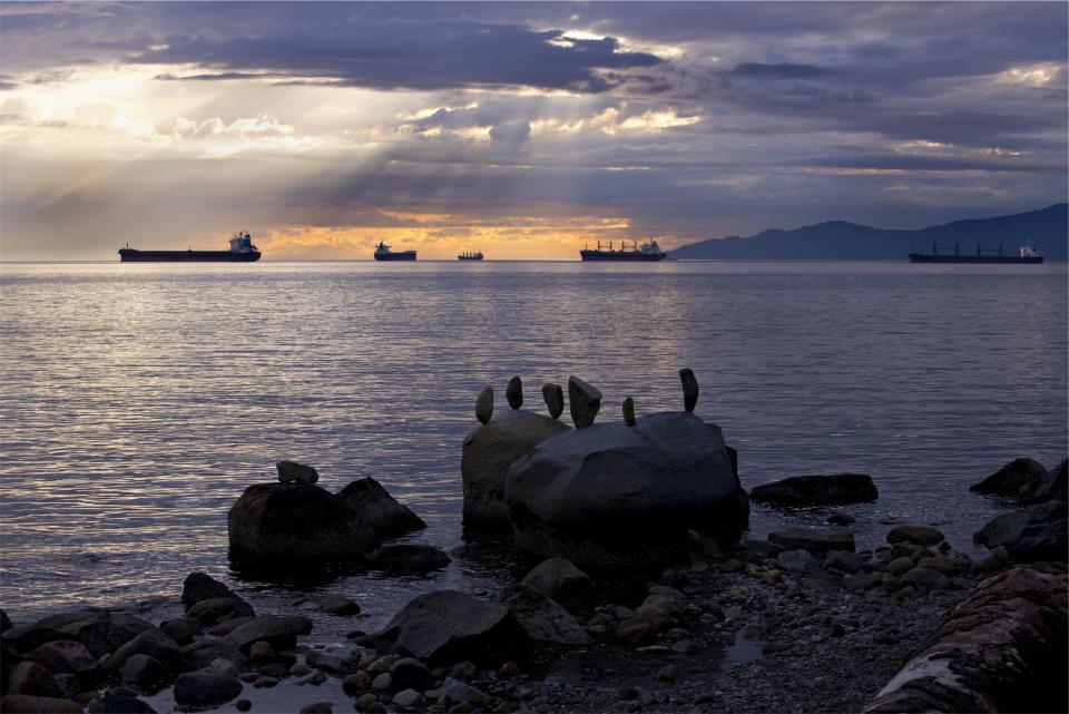 water sunset sunrays sky shore ships sea rocks ocean dusk clouds boulders boats 