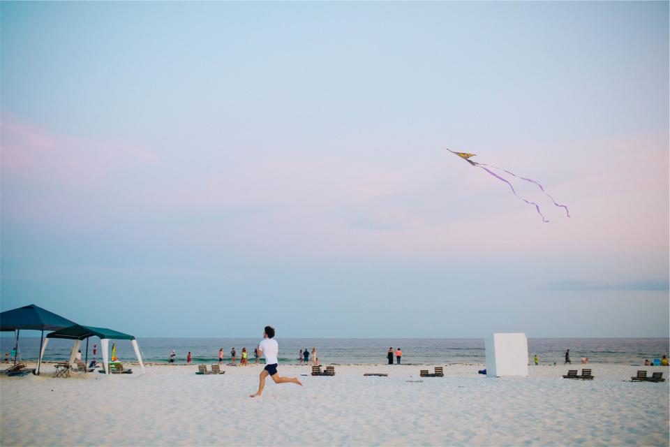 water sky shore sand running people ocean kite guy beach 