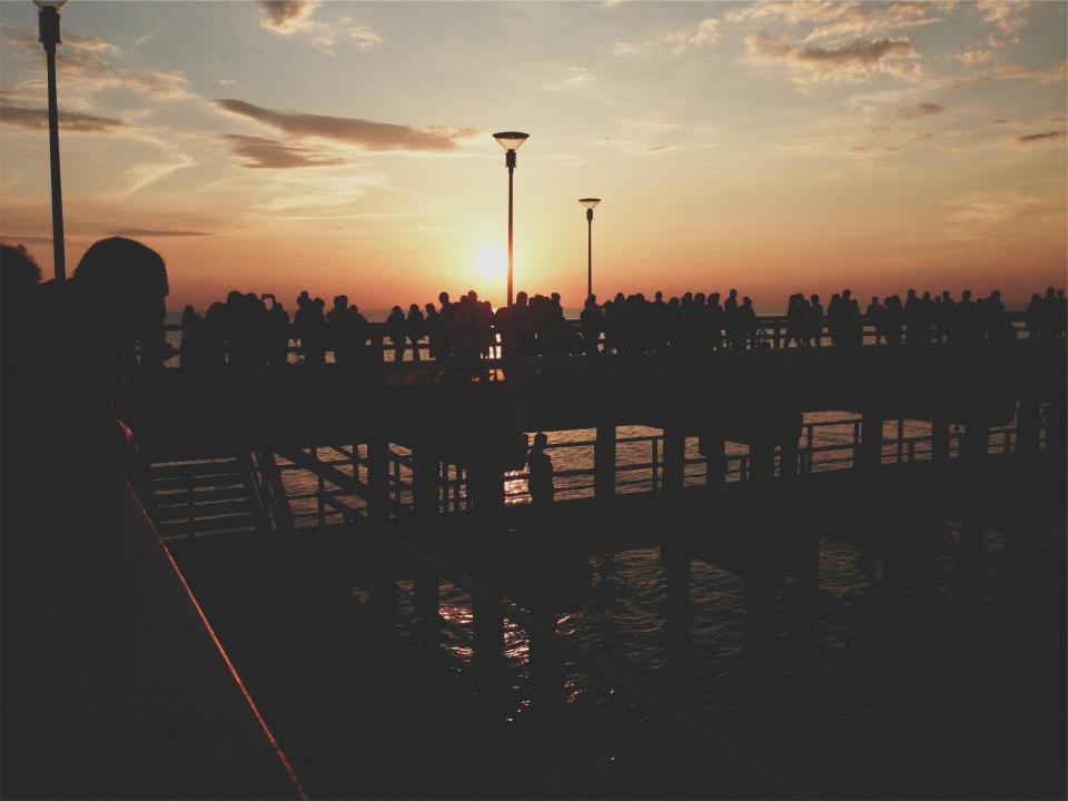 sunset sky silhouette shadows pier people lampposts dusk crowd 