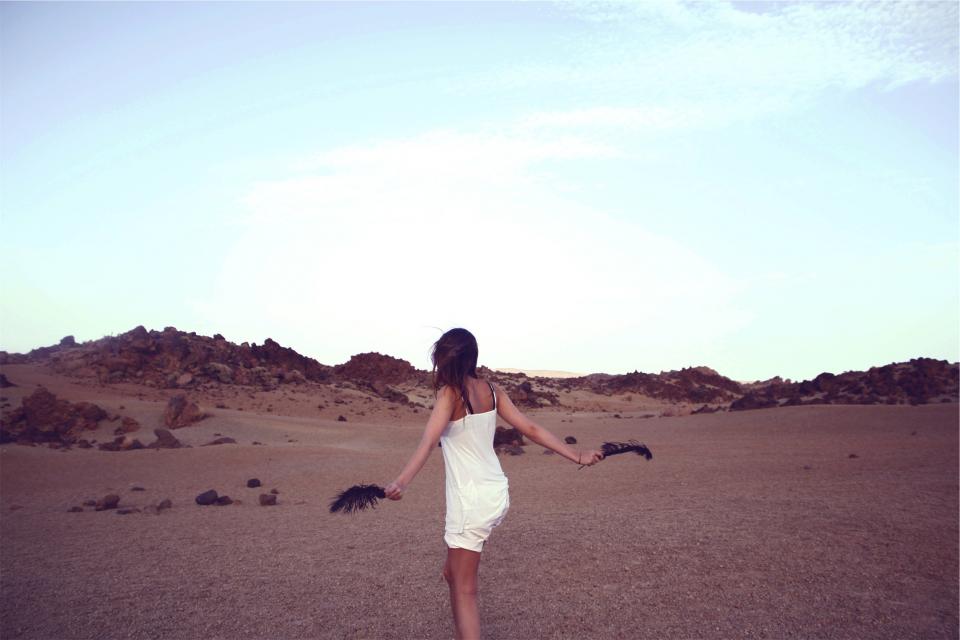young woman white tanktop sky shorts rocks people longhair girl feathers desert brunette 