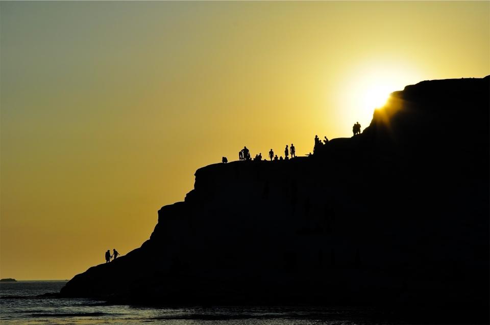 water sunset sky silhouette shore shadows people ocean mountains dusk coast cliffs beach 