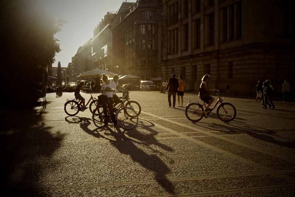 sunset summer streets shadows road people pedestrians pavement city buildings bikes bicycles 