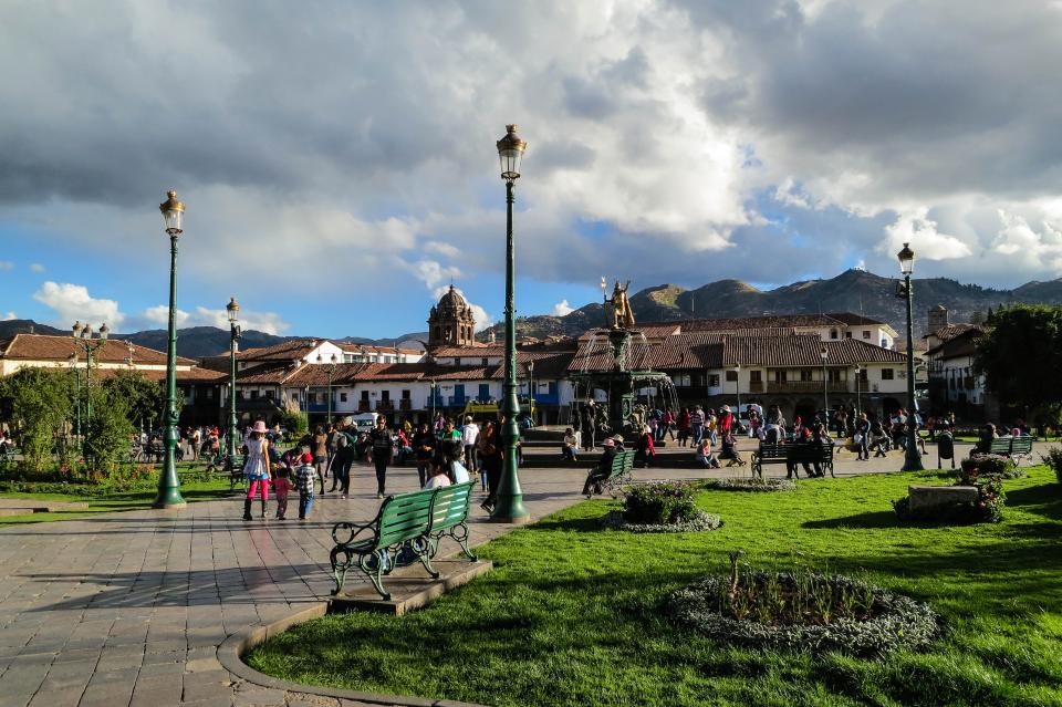 Plaza de Armes, Cusco, Peru, lamp posts, benches, grass, path, people, pedestrians, crowd, buildings, town