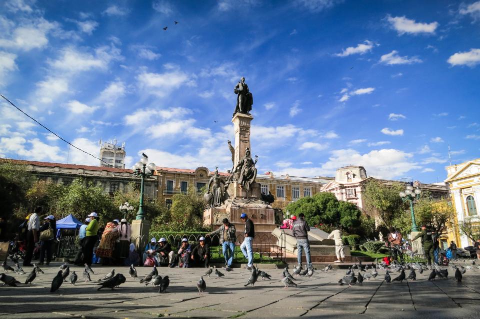 urban statue pigeons people pedestrians monument LaPaz landmark city buildings Bolivia birds architecture 
