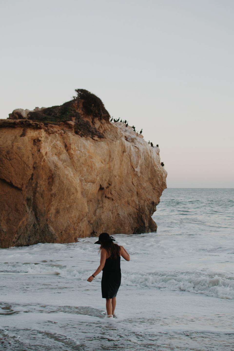 woman waves water sea rocks people ocean hat girl dress coast cliffs birds beach 