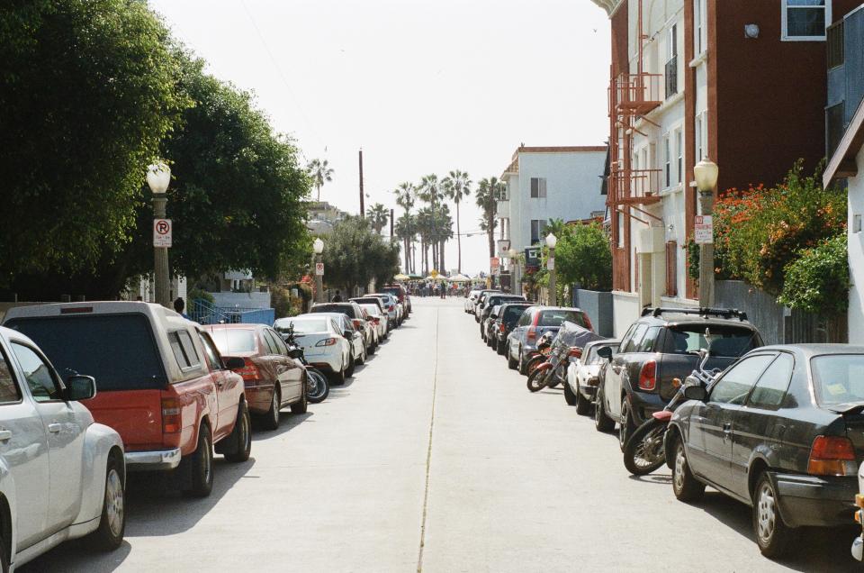 trucks sunshine street parking palmtrees motorcycle houses cars buildings apartments 