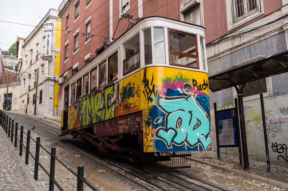 trolley tramcar streetcar lisbon graffiti cobblestone city buildings 