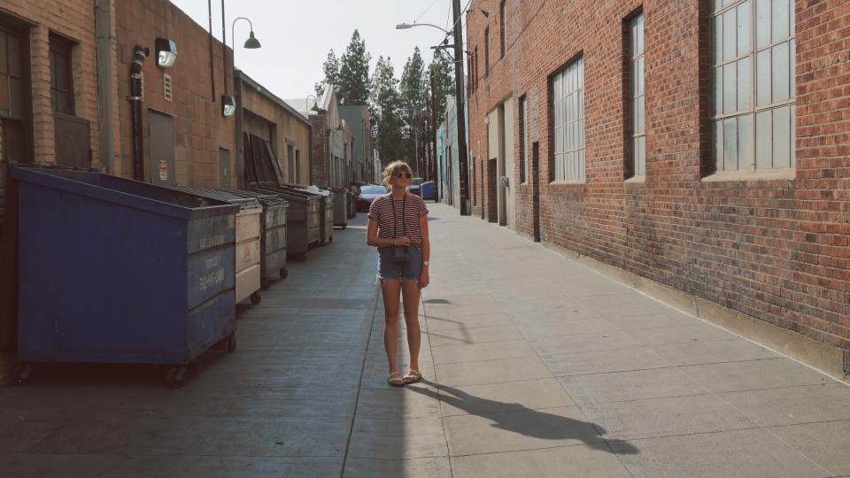 woman Windows walls sunglasses sandles jeanshorts girl dumpsters concrete camera buildings bricks alley 