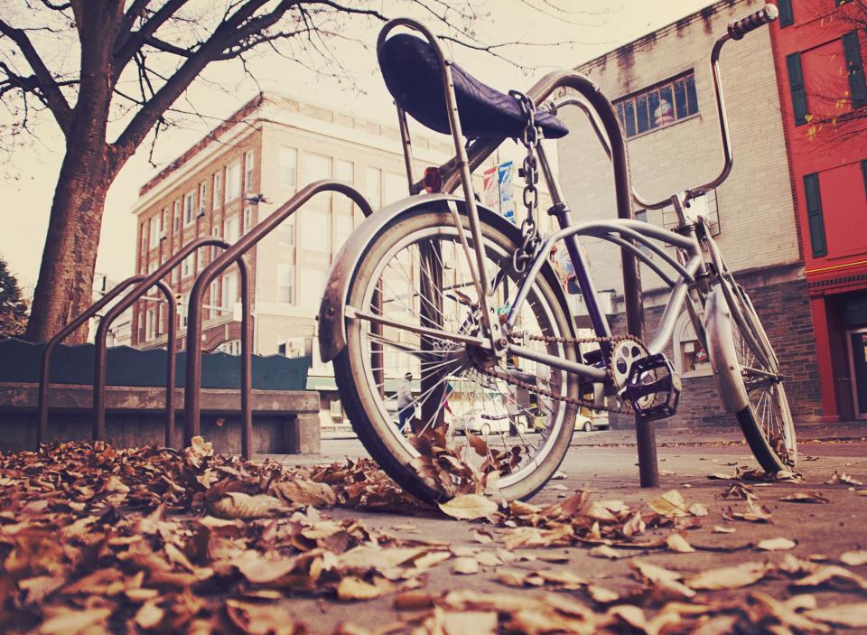 railing pavement leaves hanldebars concrete chain buildings bike bicycle 