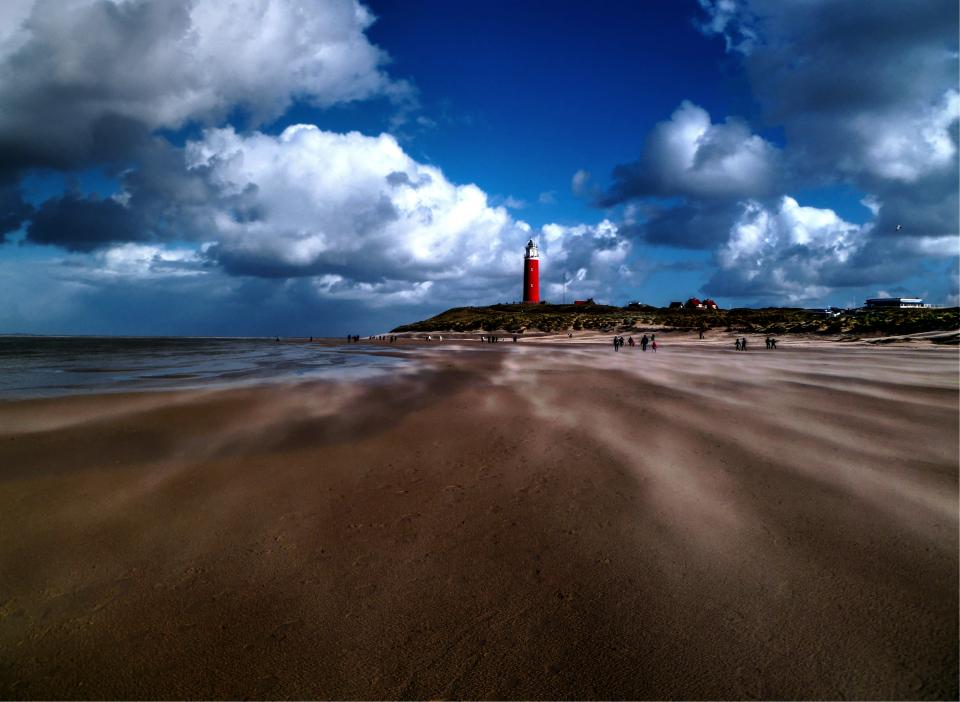 water sky sea sand people ocean lighthouse clouds beach 