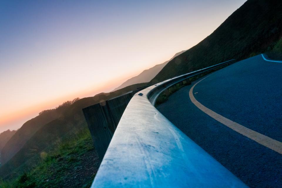 winding sunset sky road railing mountains guardrail dusk corner 