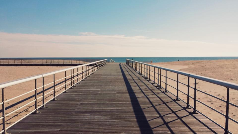 wood water sunny summer sky sand railing planks ocean clouds boardwalk blue beach 