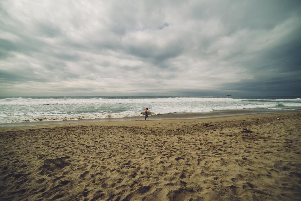 waves surfer surfboard sea sand ocean cloudy clouds beach 